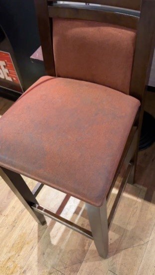 Another angle of a venue bar chair with a grime-darkened seat, before cleaning