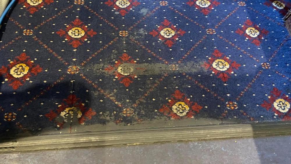 A social club's patterned carpet, heavily soiled at the doorway, before cleaning