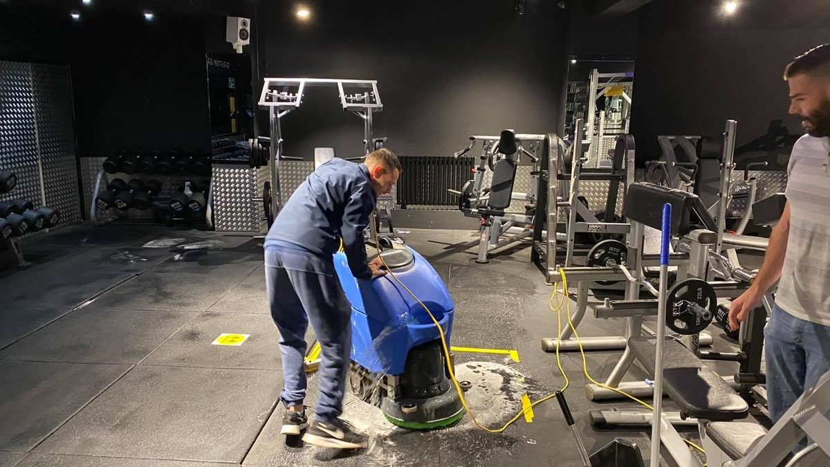 Deep-scrubbing a gym floor between the machines