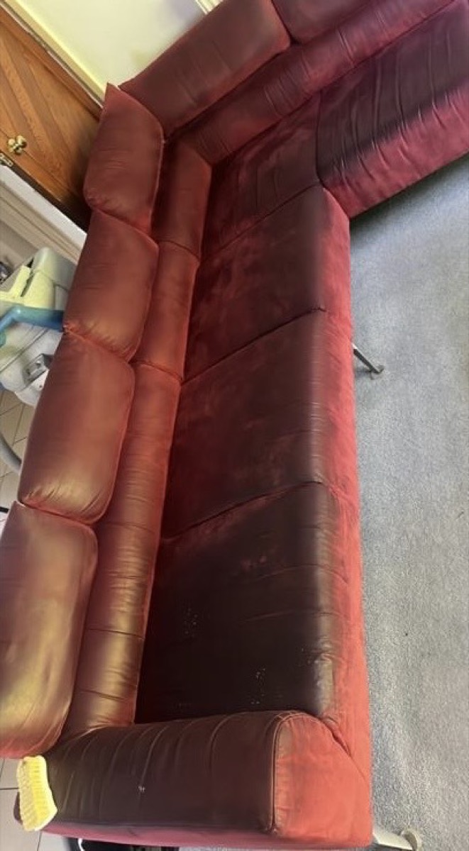 A red corner sofa before cleaning. Dull and grubby
