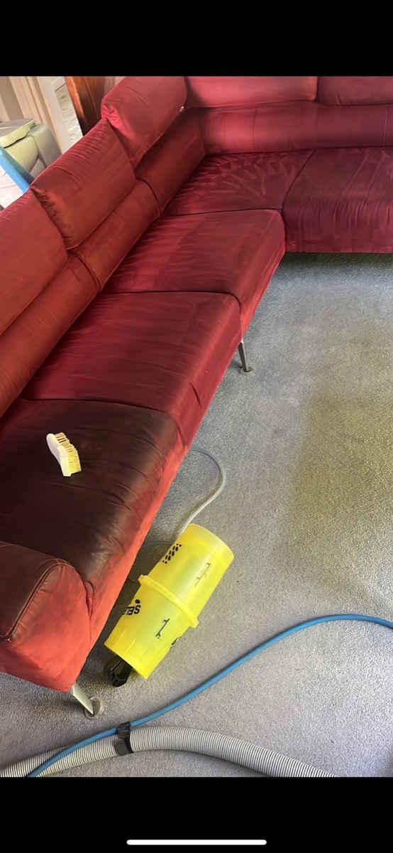 The same red sofa during cleaning, half brushed and hot-water extracted