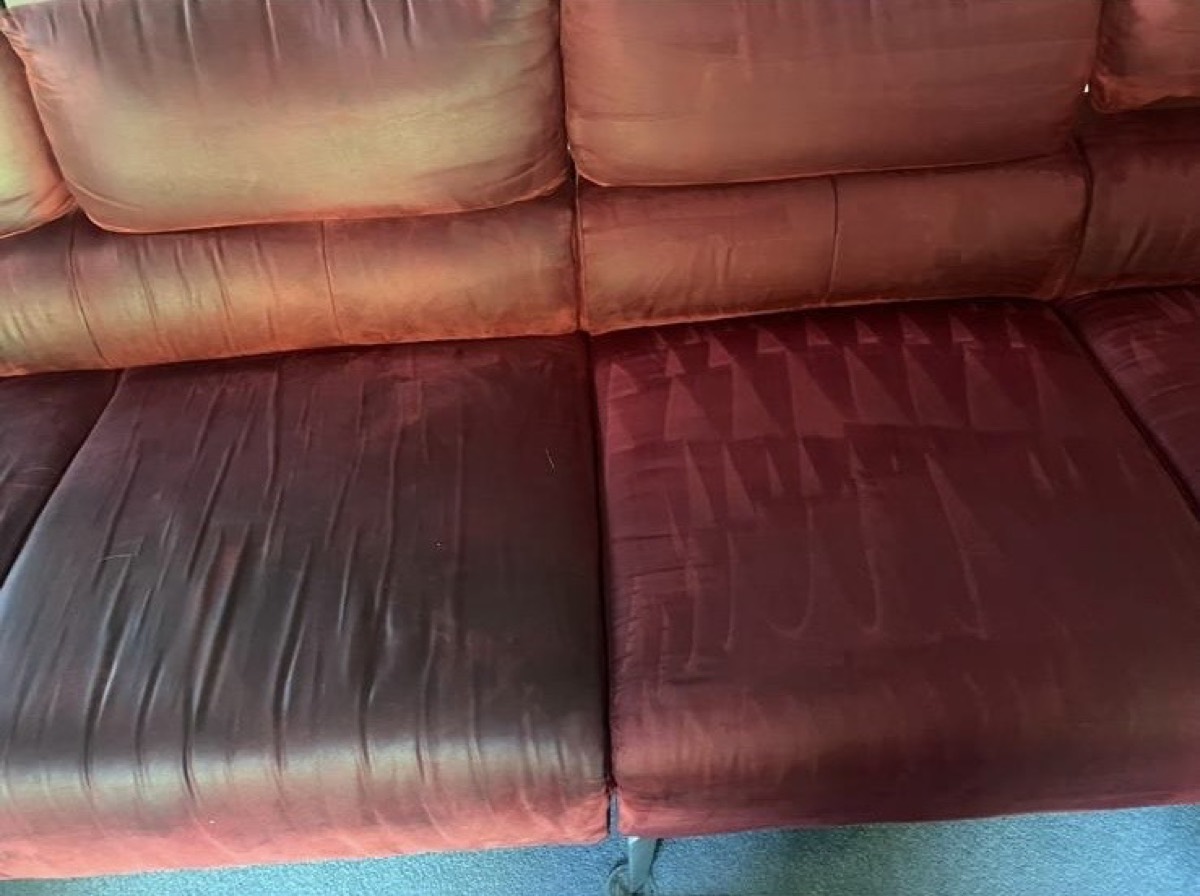 A red velvet sofa mid-clean, the right cushion refreshed, the left still to do