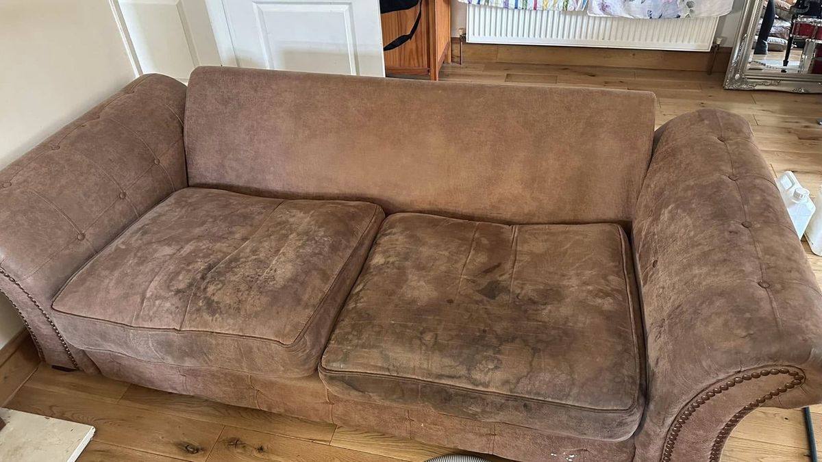 The same brown sofa before cleaning, heavily stained seat cushions