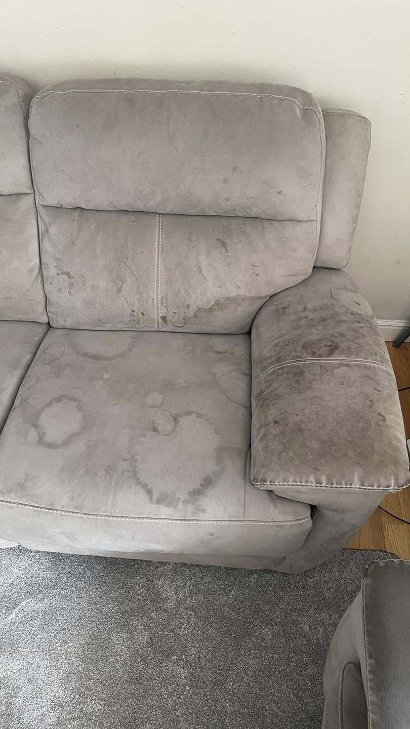 A grey sofa before cleaning, stains on seat and arm