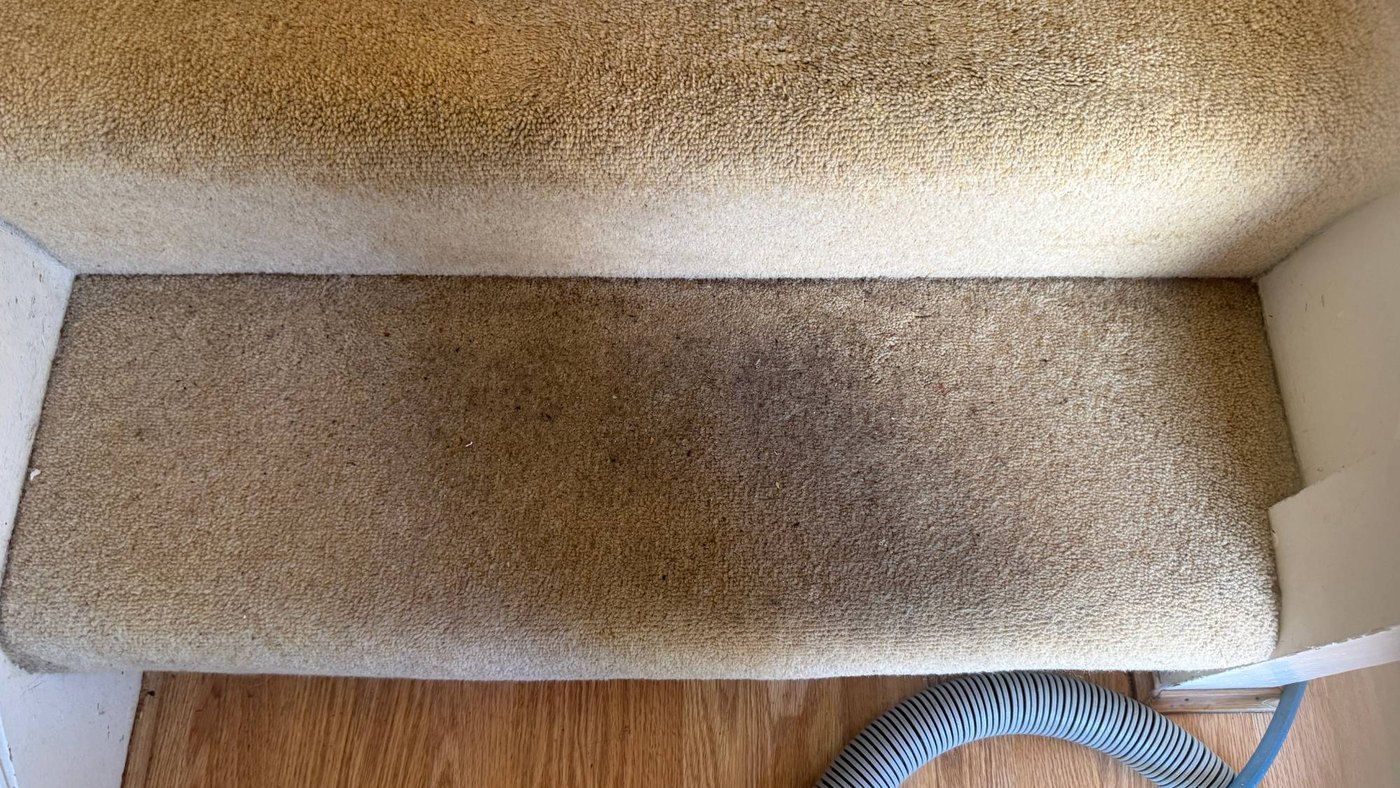 A stair tread worn dark with traffic before cleaning by Jay's Cleaning